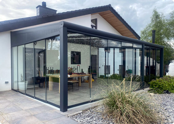 pergola fermée sur la façade avant d'une maison en crépis blanc